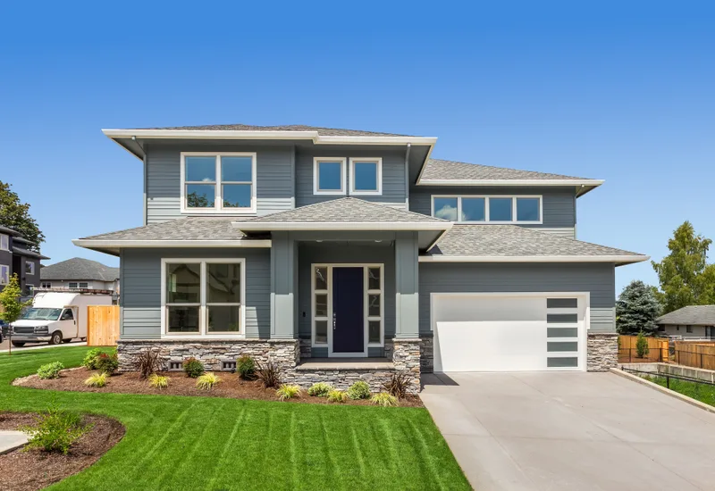 A two-story suburban home with a green, freshly mowed front lawn and a wide driveway