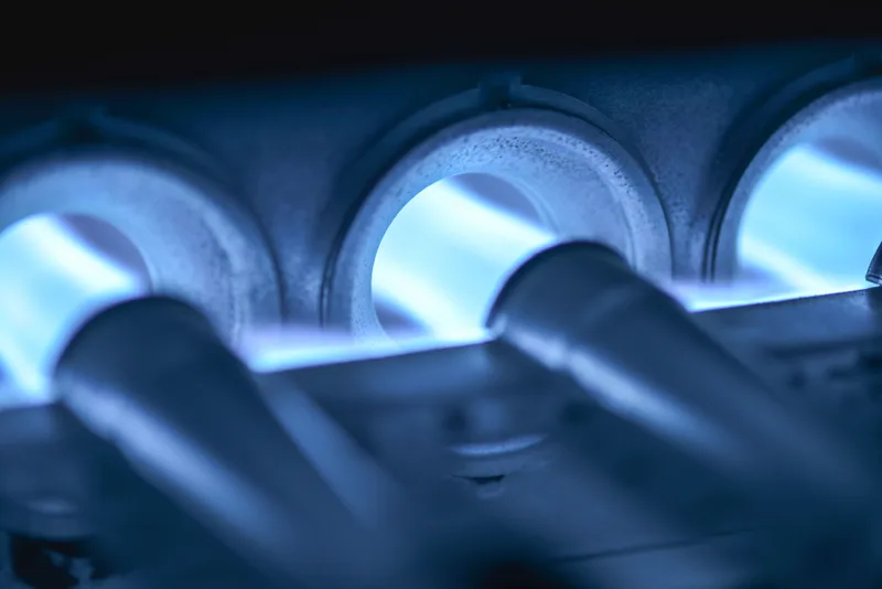 Close-up of blue gas burner flames inside a furnace