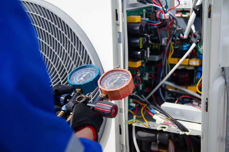 Technician reading refrigerant pressure gauges on an open outdoor unit
