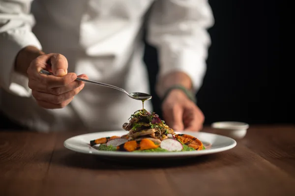 Chef plating a dish in a busy restaurant kitchen