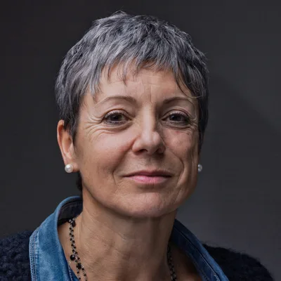 Portrait of Ruth Ostrowski, short grey hair, against a dark background