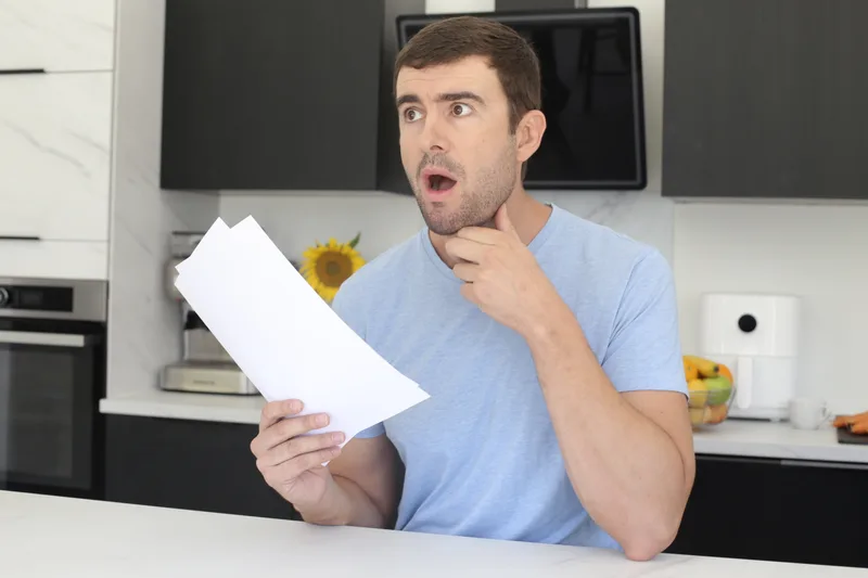 A man at his kitchen table reads a letter from work