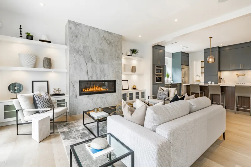 Bright open-plan living room with a white sofa, glass coffee table and a stone fireplace wall