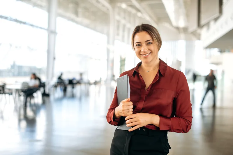 Portrait of attorney Hallie Brandt holding a folder in an open office