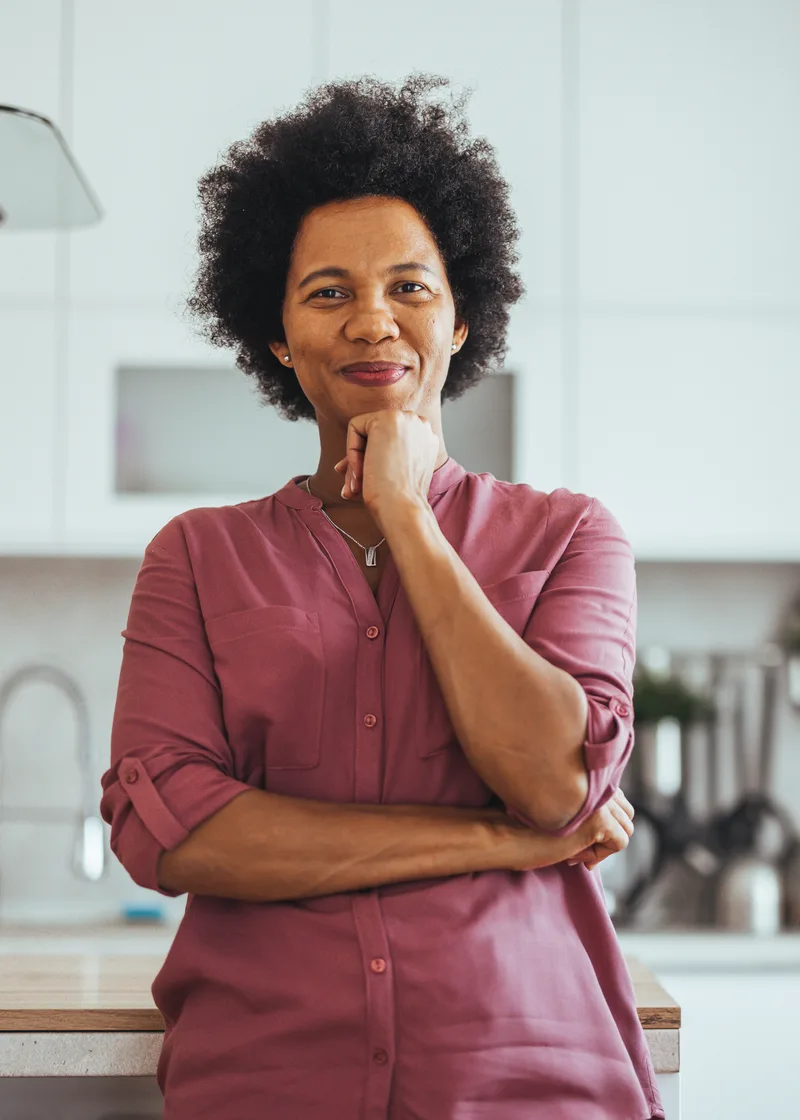 A home business owner stands in her kitchen with her hand at her chin