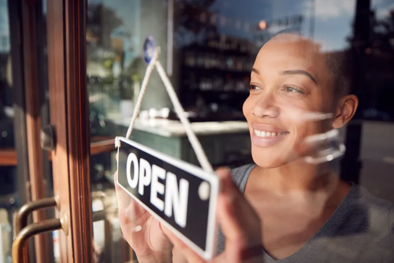 A shop owner turns her door sign to Open