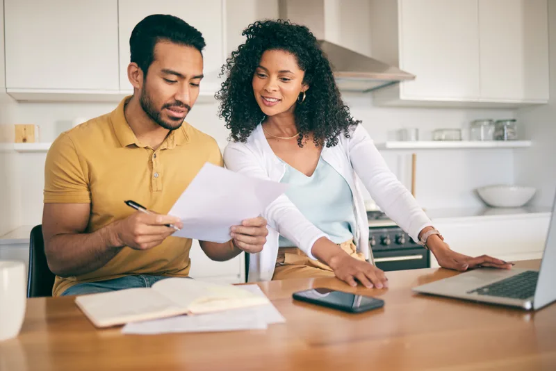 Couple at their kitchen counter sorting through bills and papers together