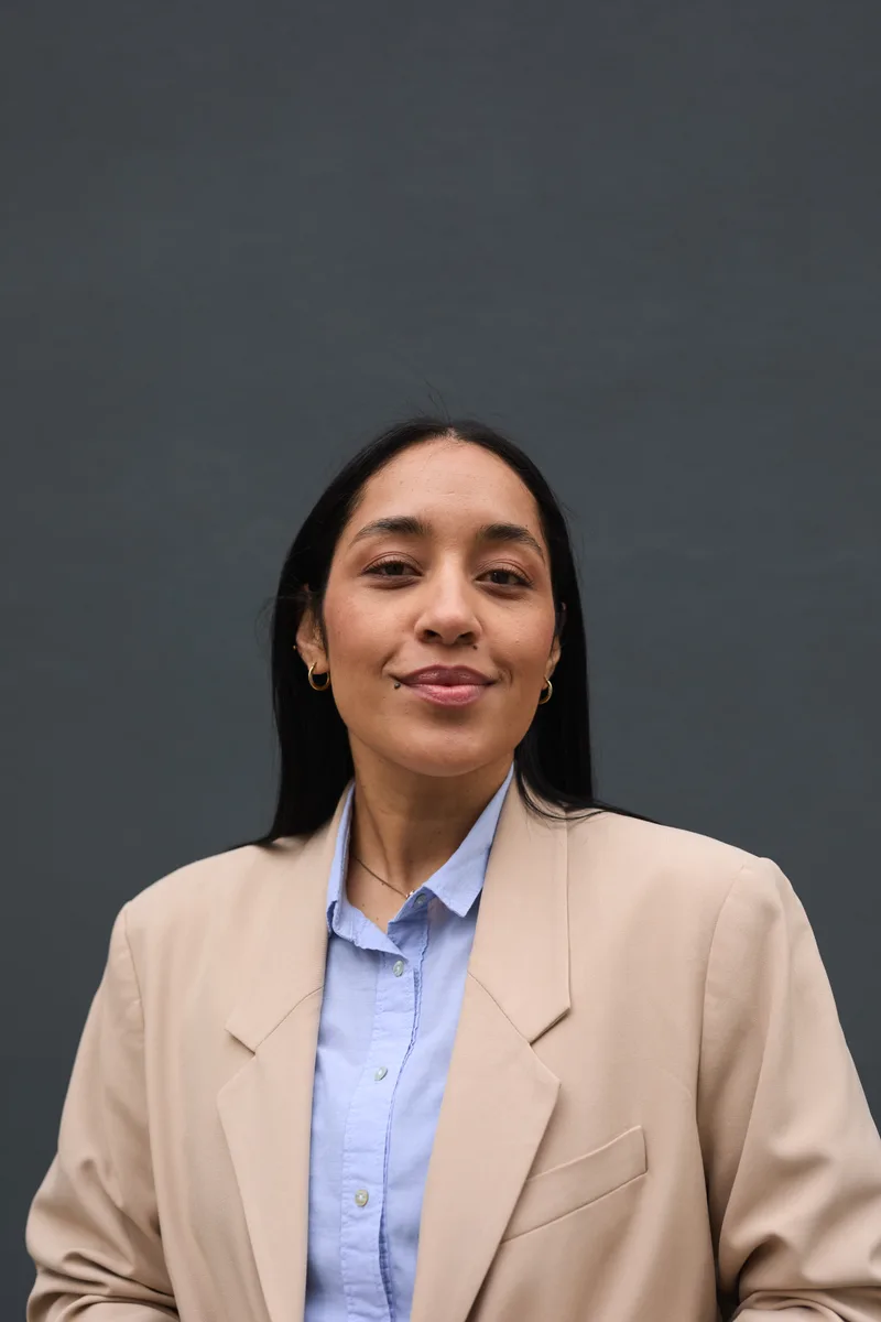 Daniela Ruiz, an attorney with long dark hair in a beige blazer, smiling at the camera