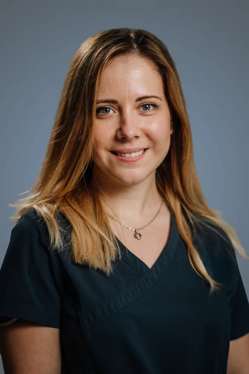 Portrait of attorney Claire Hollis, smiling, in a dark top against a grey background