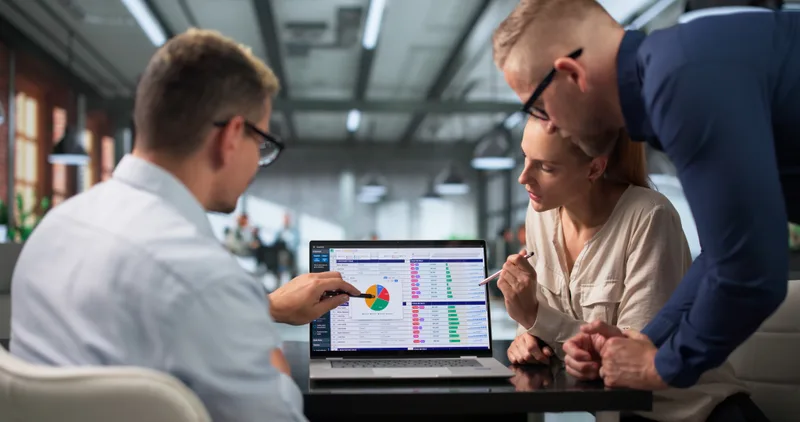 A billing analyst and two colleagues review coding spreadsheets on a laptop