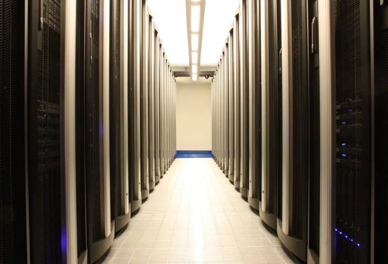 A long aisle between rows of server racks in a data center