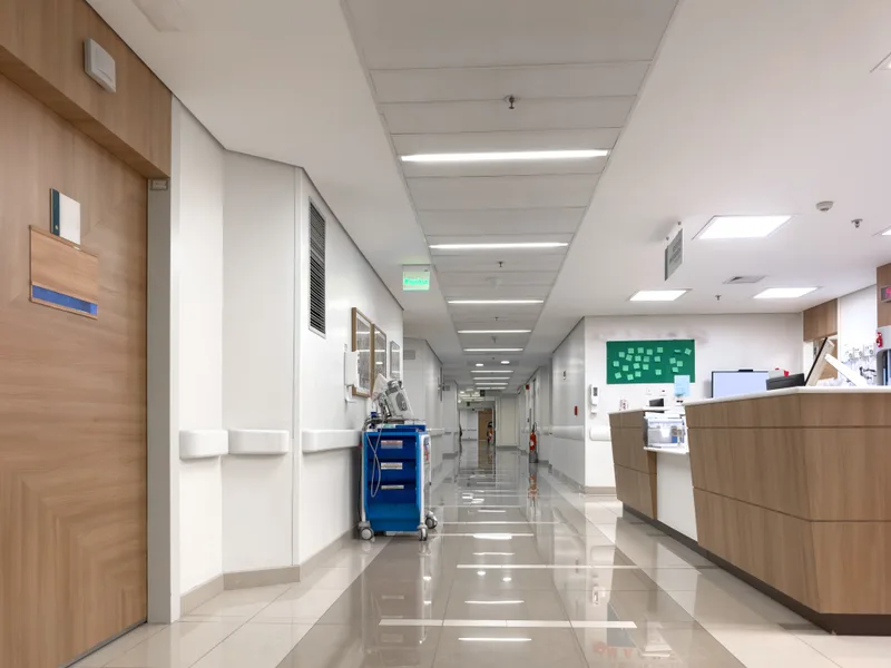 A quiet hospital hallway with a nurses' station and a medication cart