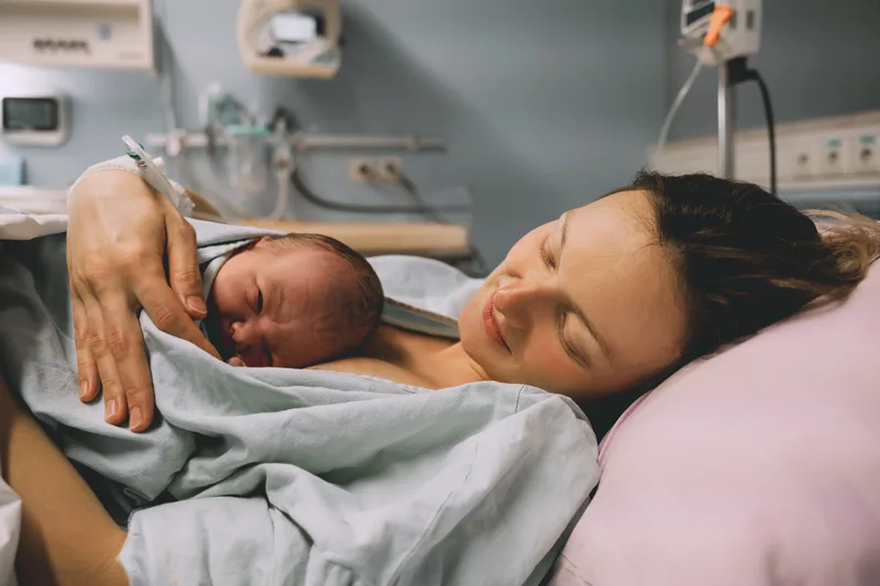 A mother resting in a hospital bed with her newborn on her chest