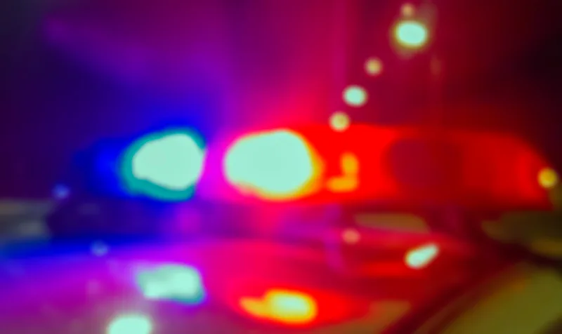 Red and blue emergency lights of a police cruiser glowing against the dark at a night-time accident scene