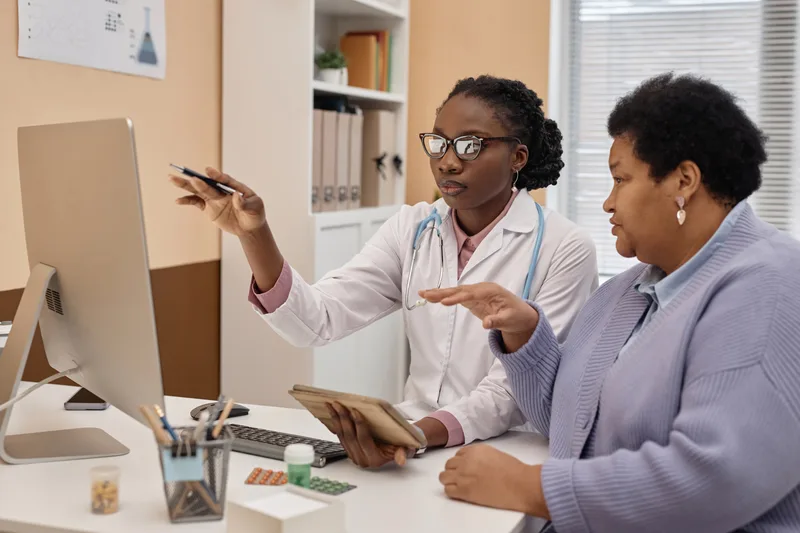 A doctor going over test results on a computer screen with an older patient