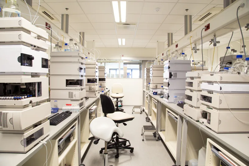 An empty pharmaceutical testing laboratory with rows of analysis equipment