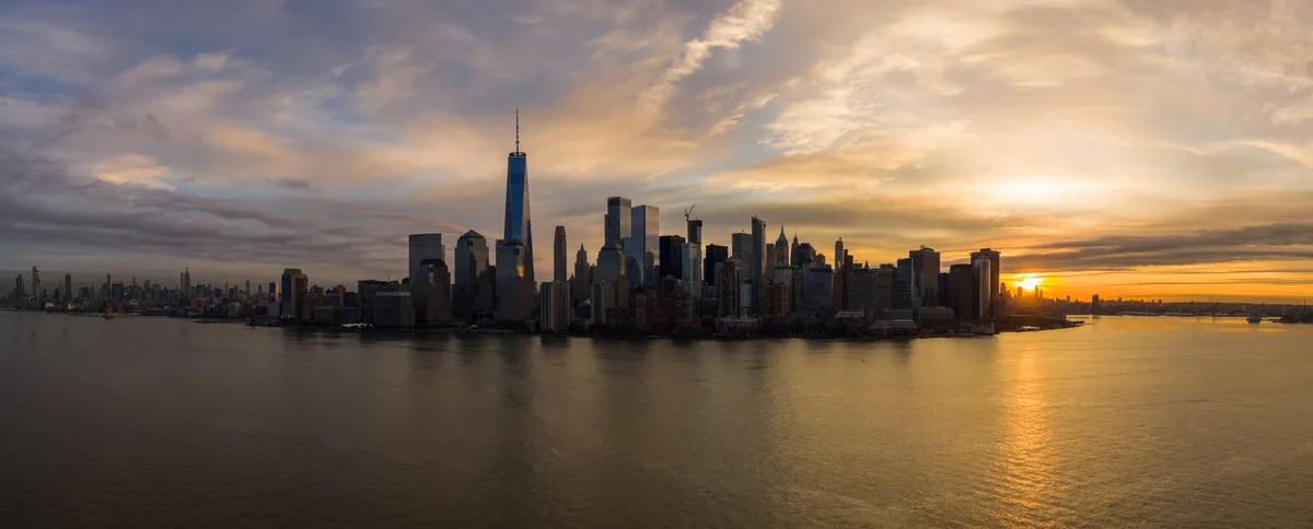 Panorama of the Lower Manhattan skyline at sunset, seen across the harbor from the firm's side of the river