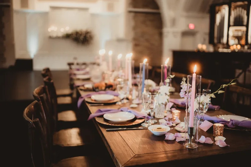 Candlelit harvest table dressed with taper candles, petals, and florals for a reception