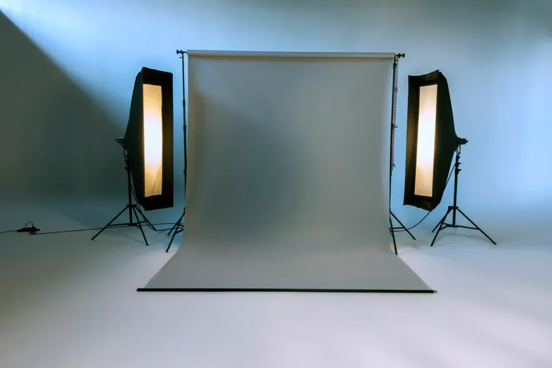 Empty photography studio with a grey seamless paper backdrop lit by two softboxes on stands