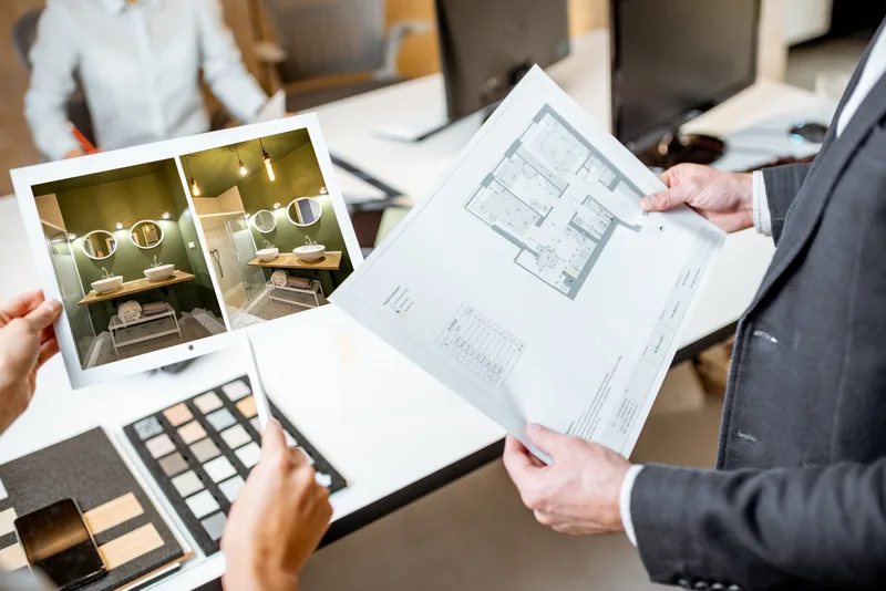 Architects comparing printed floor plans and material samples at a desk