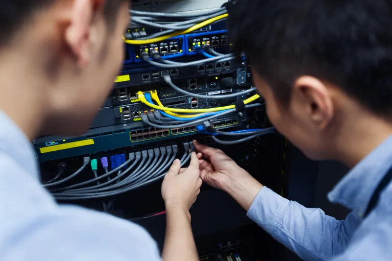 Two technicians tracing a network cable at a patch panel