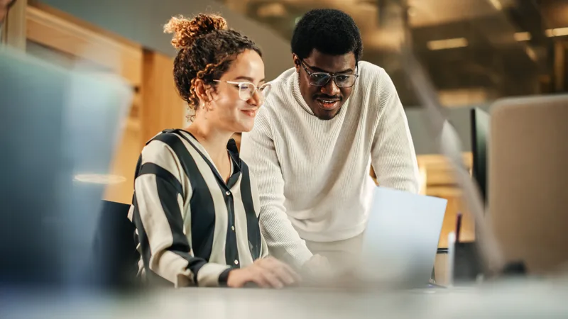 A Plainspoken technician leans in to walk an office manager through a fix on her laptop