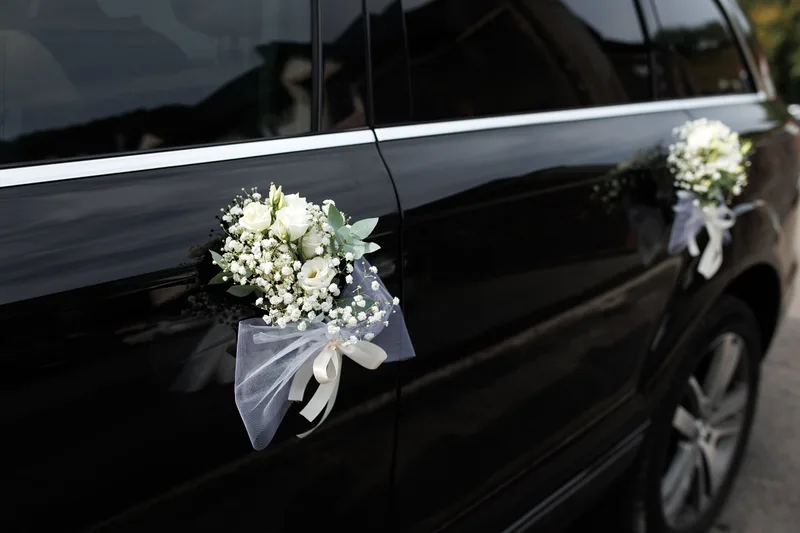White posies tied to the doors of a black wedding car