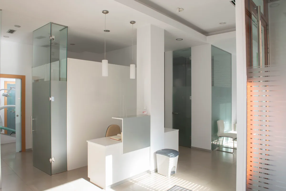 Reception at the Leaside Studio — white desk and frosted-glass treatment rooms washed in afternoon sun