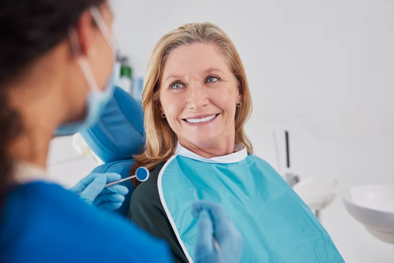 A reassured patient in the chair looking up at her dentist during an exam