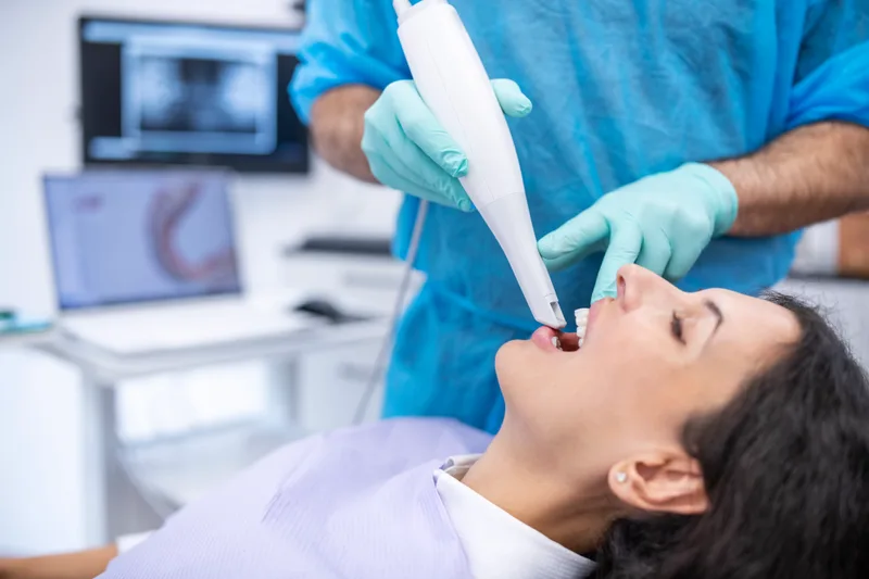 A clinician capturing a digital 3D scan of a patient's teeth with a handheld intraoral scanner