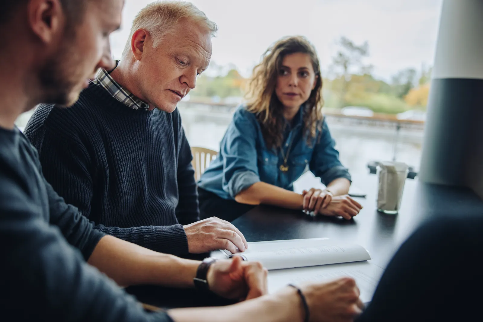Agricultural lawyer reviewing a succession plan with two generations of a farm family at a table