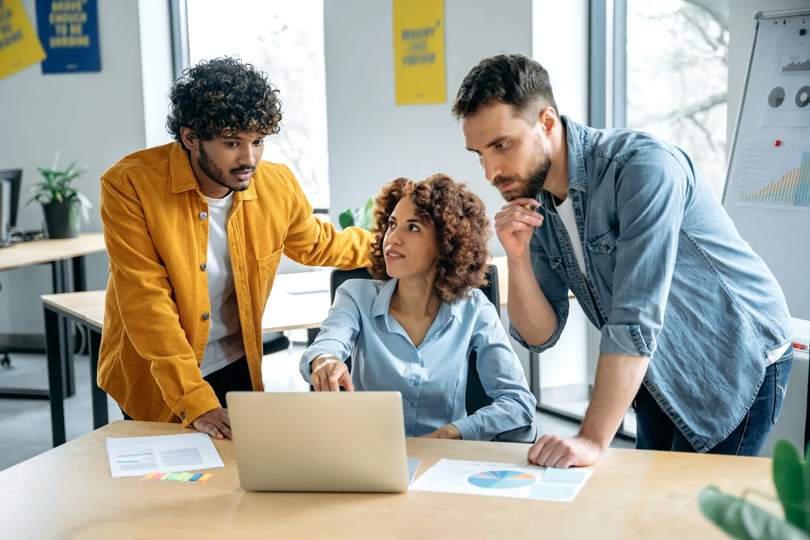 A small AI-native startup team of three reviewing product usage and signup metrics together on a laptop