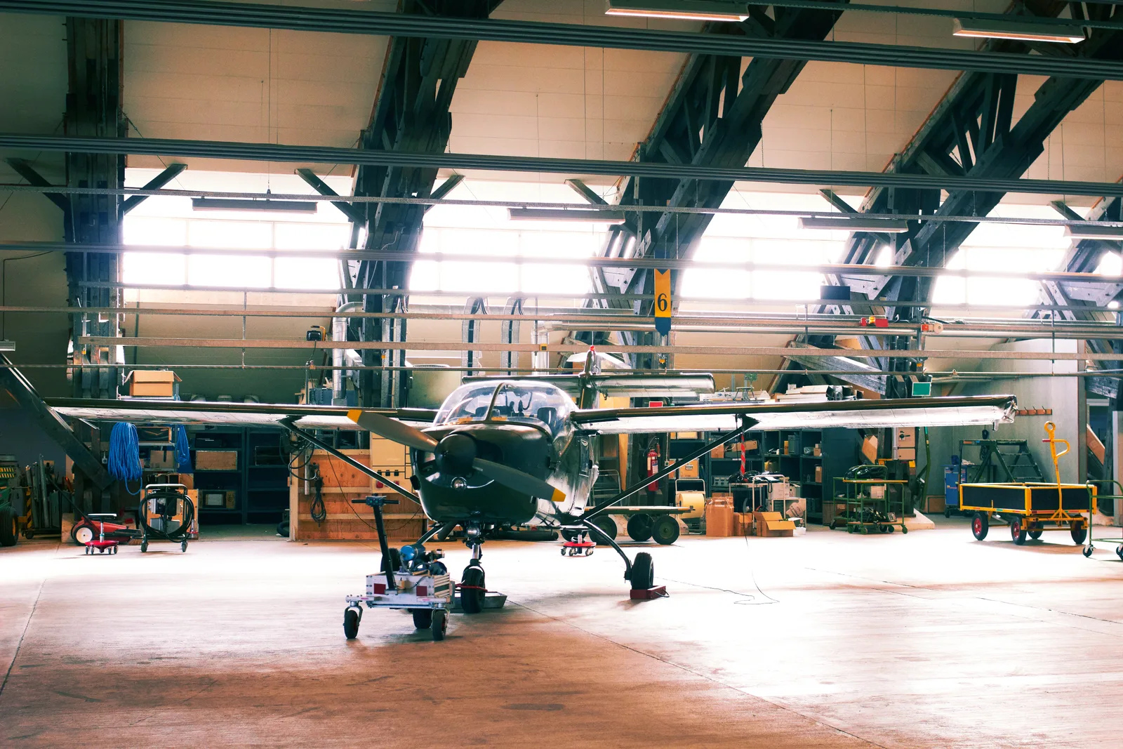 A&P mechanic inspecting a small aircraft engine with the cowling open inside a maintenance hangar