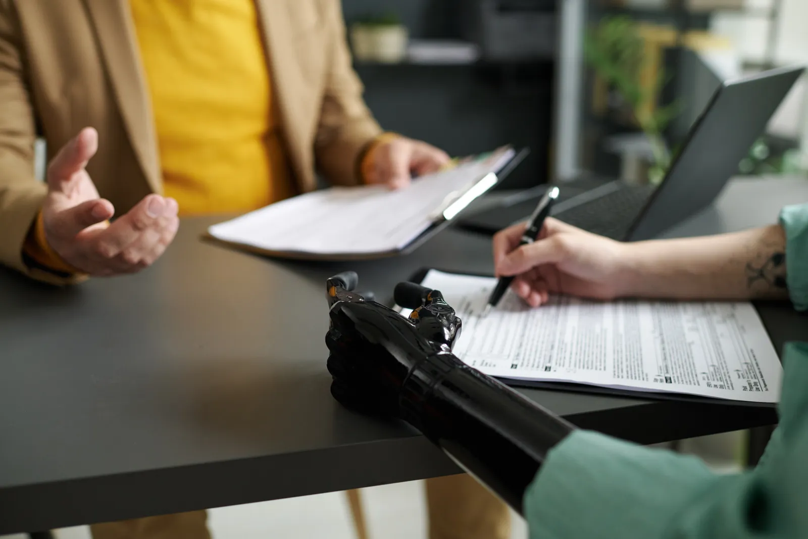 Amputation injury attorney reviewing a prosthetic care plan and medical records with a client at a law office conference table