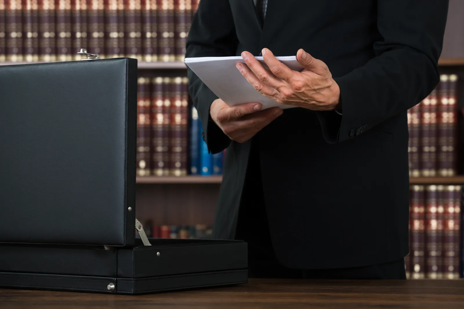 Appellate attorney with a tablet and briefcase in front of a wall of law reporters
