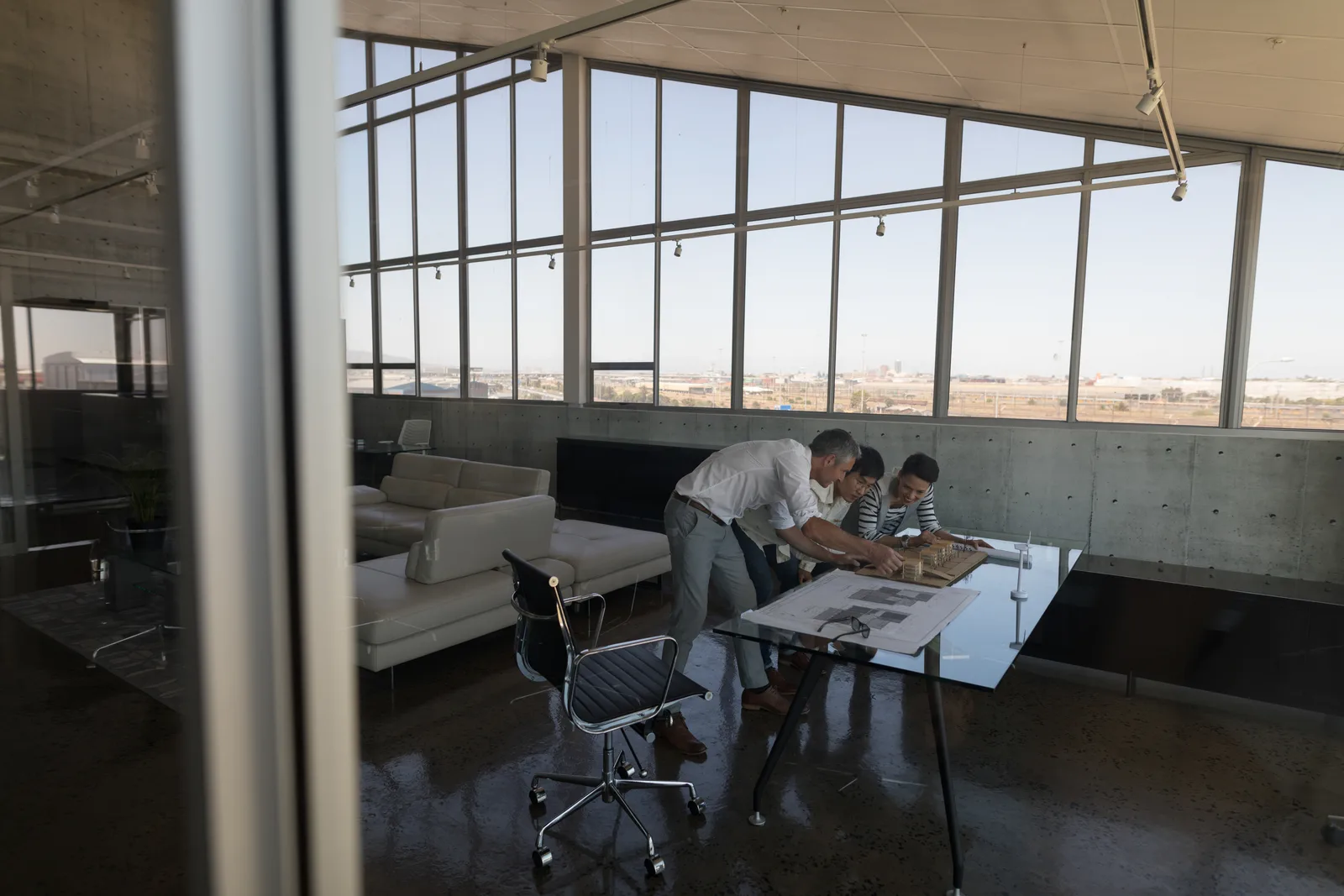 Architect reviewing building plans and material samples with clients at a studio table