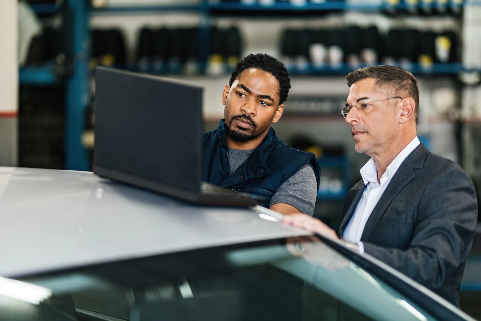 Dealership general manager and controller reviewing sales, F&I, and service data together on a dealer management system dashboard