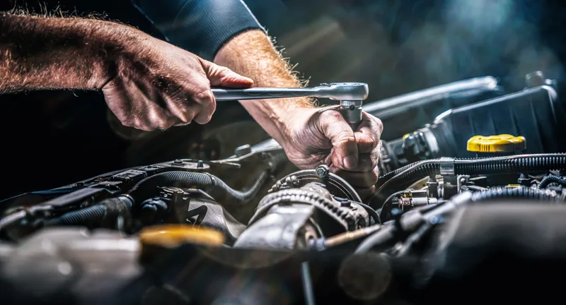 Auto mechanic working on a car engine in a repair shop garage
