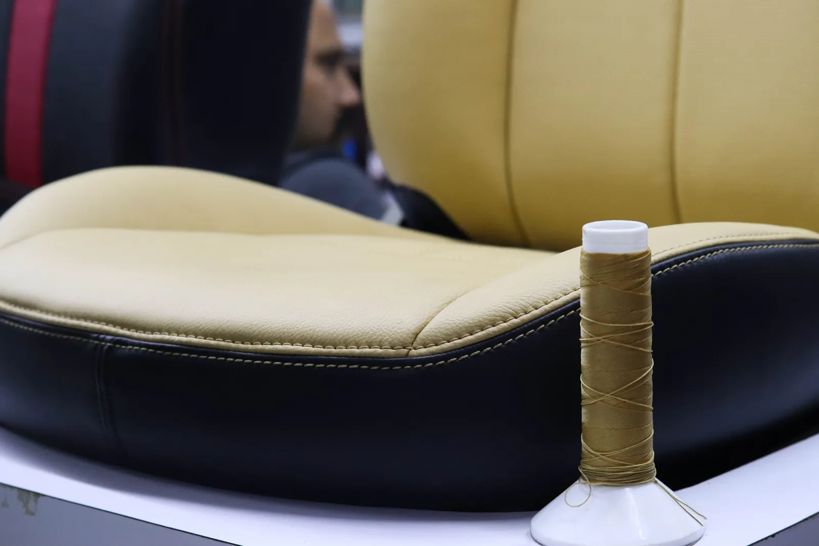 Upholsterer sewing a leather car seat cover on an industrial machine in an auto trim shop