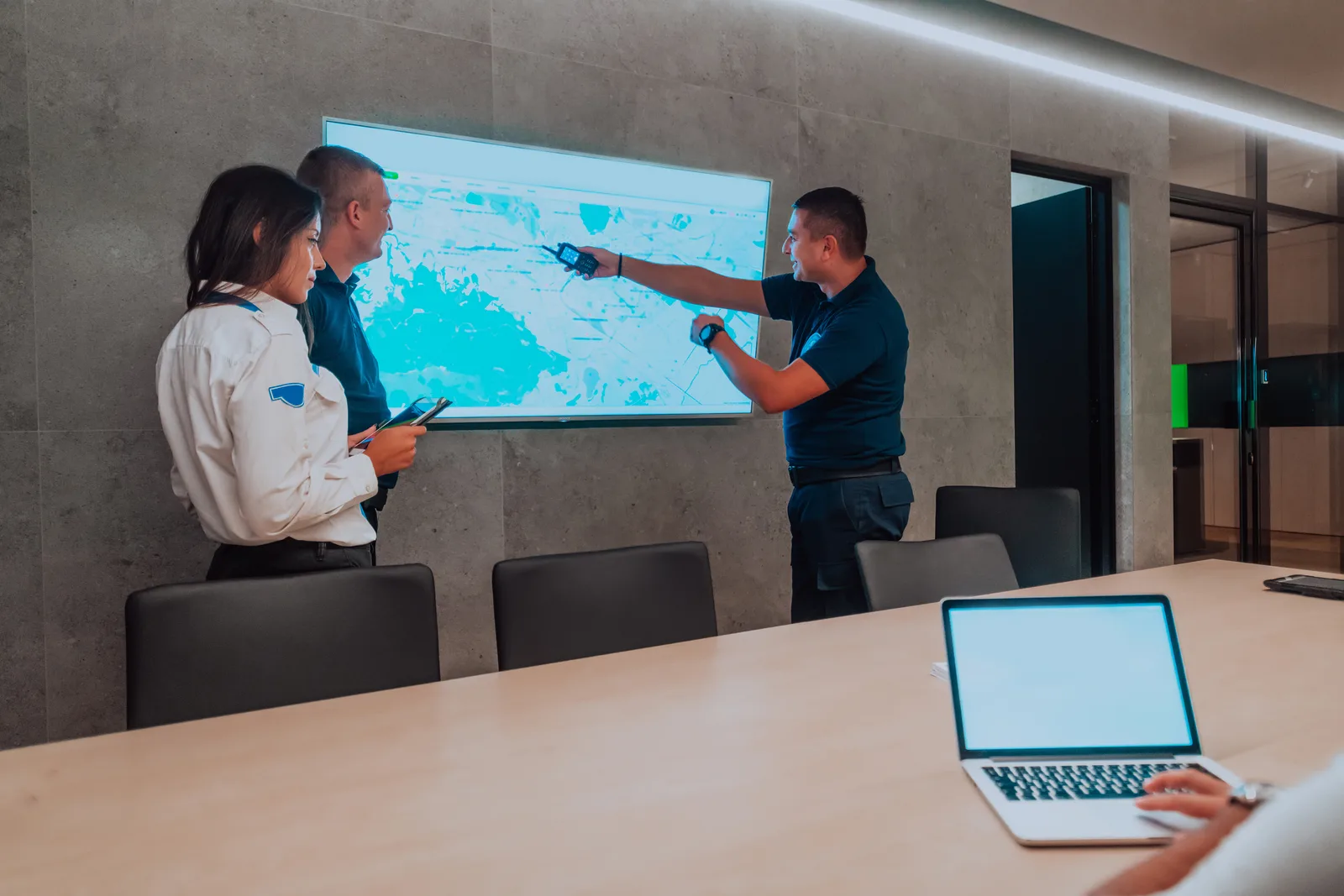 AV technician installing a video-conferencing display and control panel in a corporate boardroom