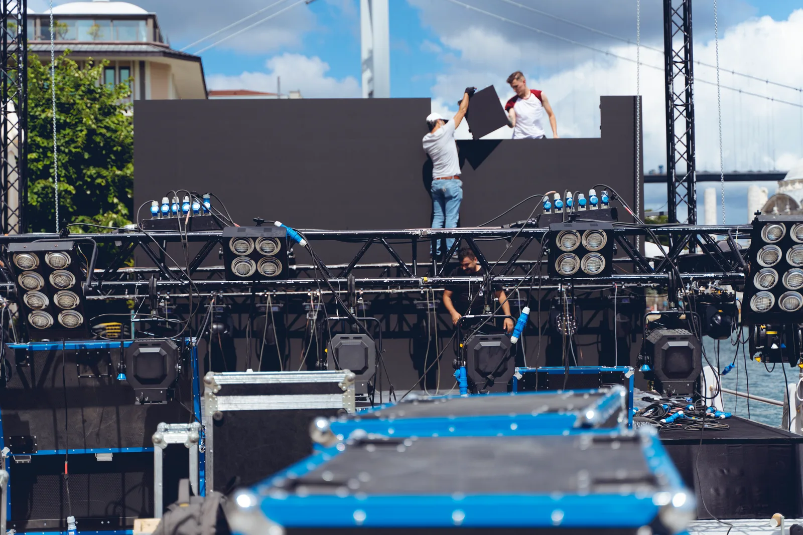 AV crew setting up a large LED video wall and stage lighting rig for a corporate event