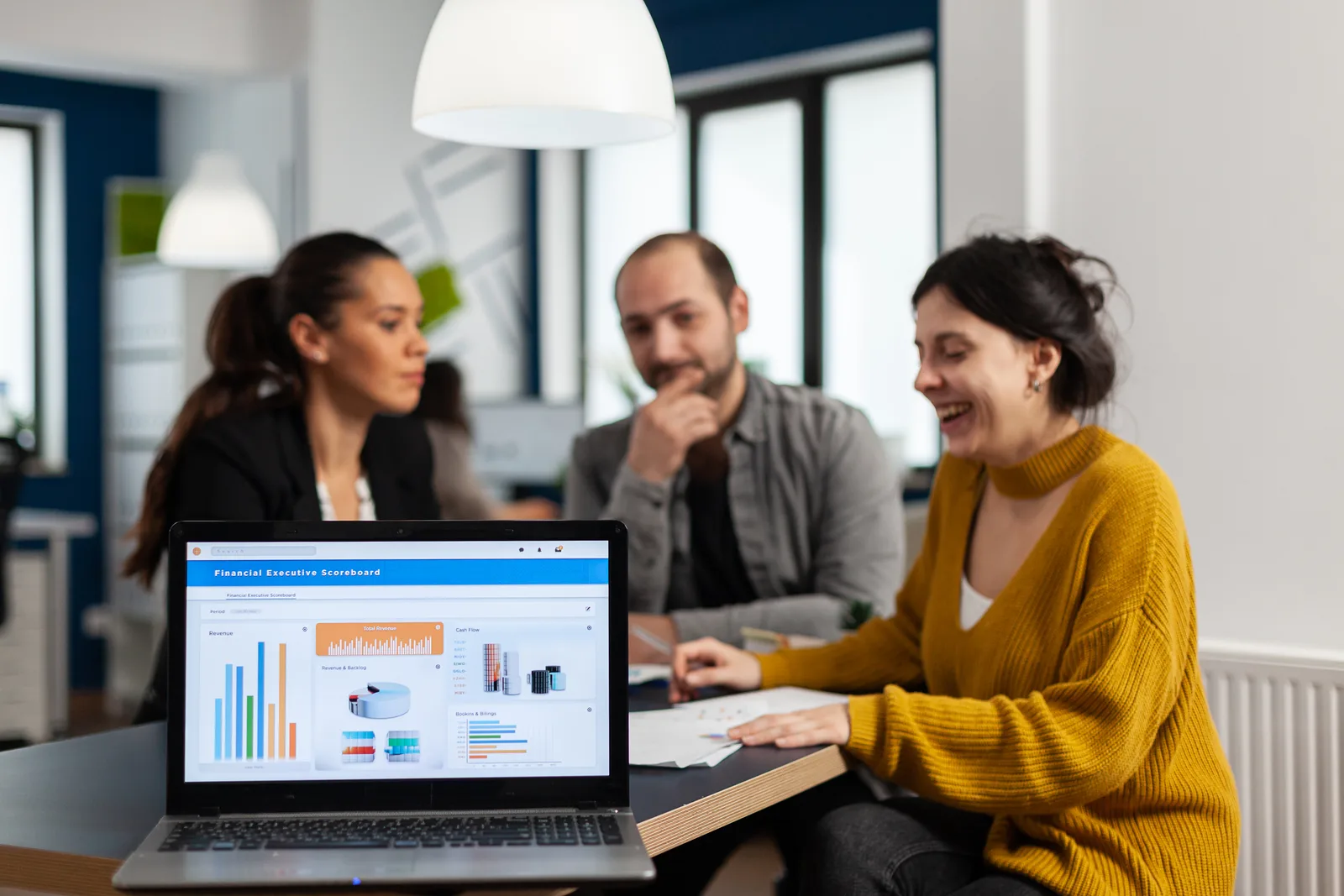 B2B SaaS sales and marketing team reviewing a pipeline dashboard together at a laptop in their office