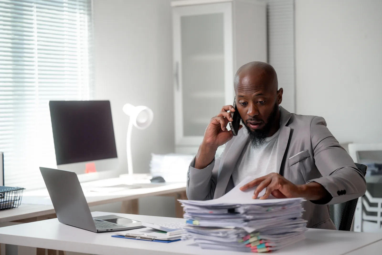 Bail bonds agent on the phone at his desk, filling out paperwork to post a client's bail
