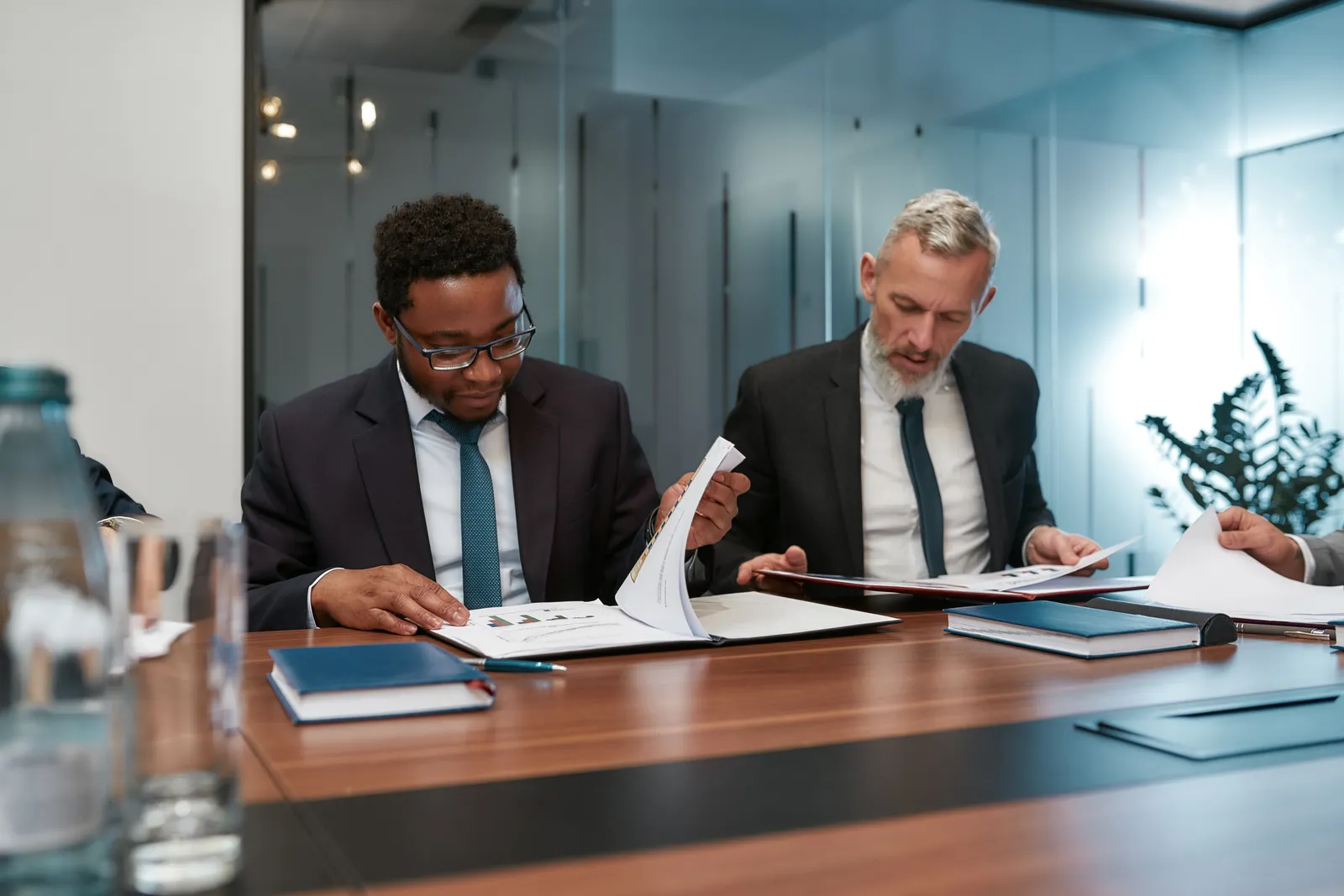Bank regulatory attorney reviewing a charter application with a bank's general counsel at a conference table