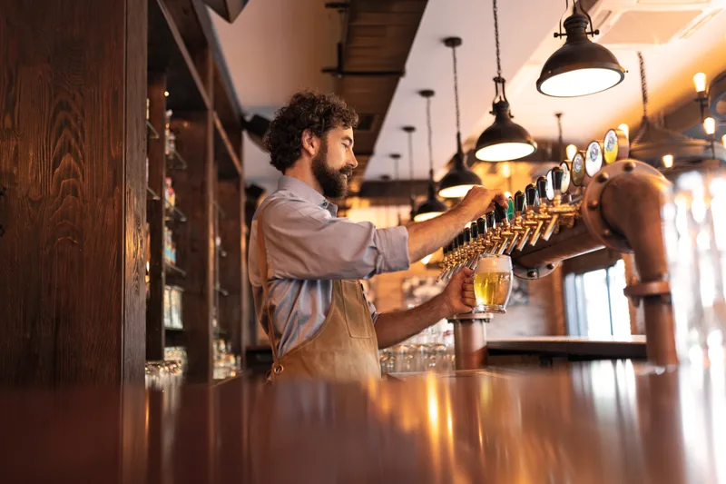Bartender pouring craft beer from a tap at a brewery
