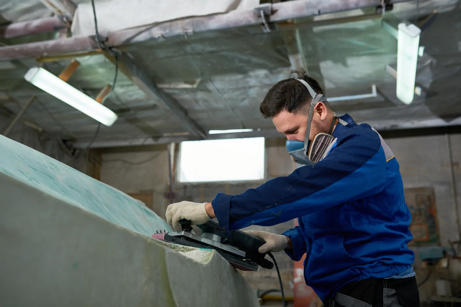 Detailer hand-polishing a boat hull to a glossy shine on a marina dock