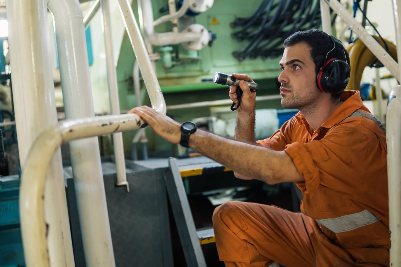 Marine mechanic's hands working on an outboard motor mounted on a boat lift in a repair shop bay