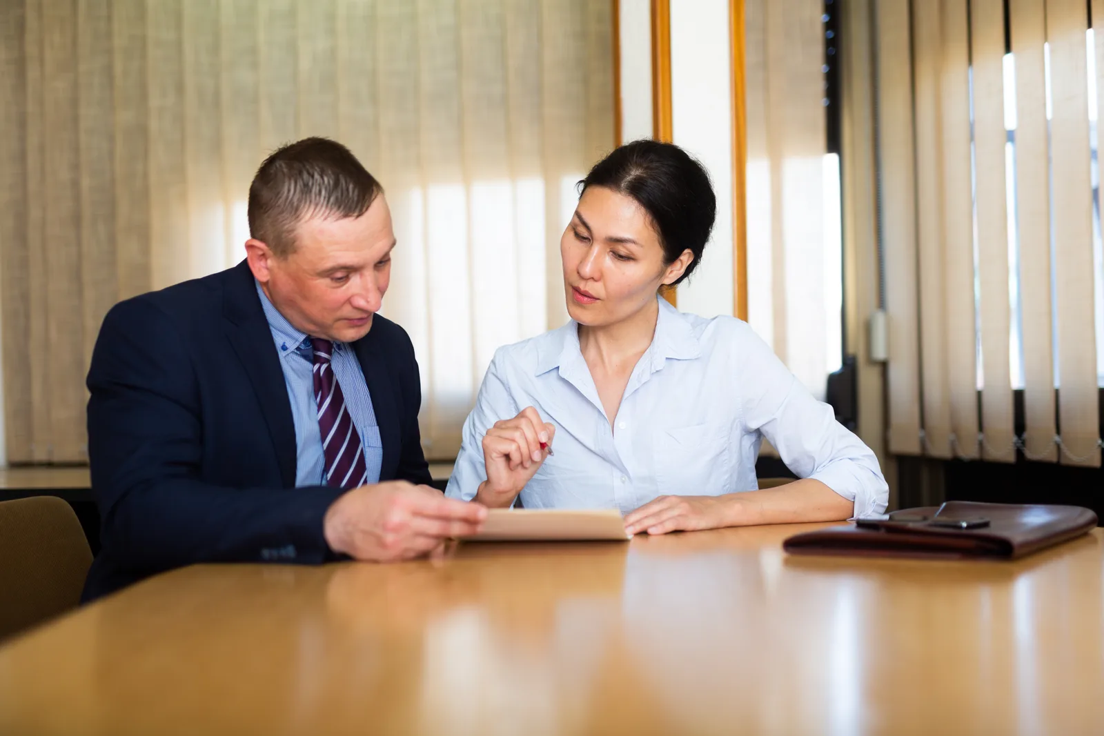 Boating accident lawyer reviewing a Coast Guard accident report and vessel photos with an injured client at a law office conference table