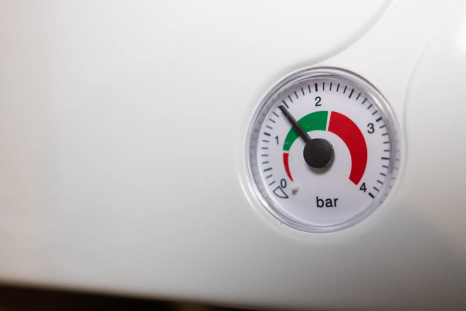 Technician checking the pressure gauge and pipework on a home gas boiler during a service visit