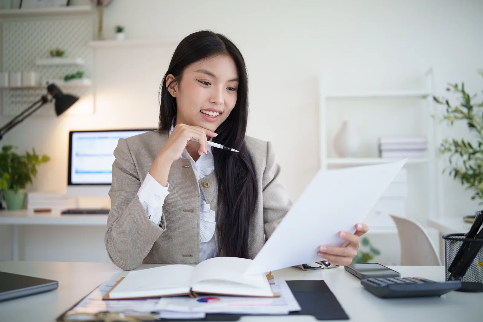 Bookkeeper reviewing a small-business client's monthly financial statements on a laptop at her desk